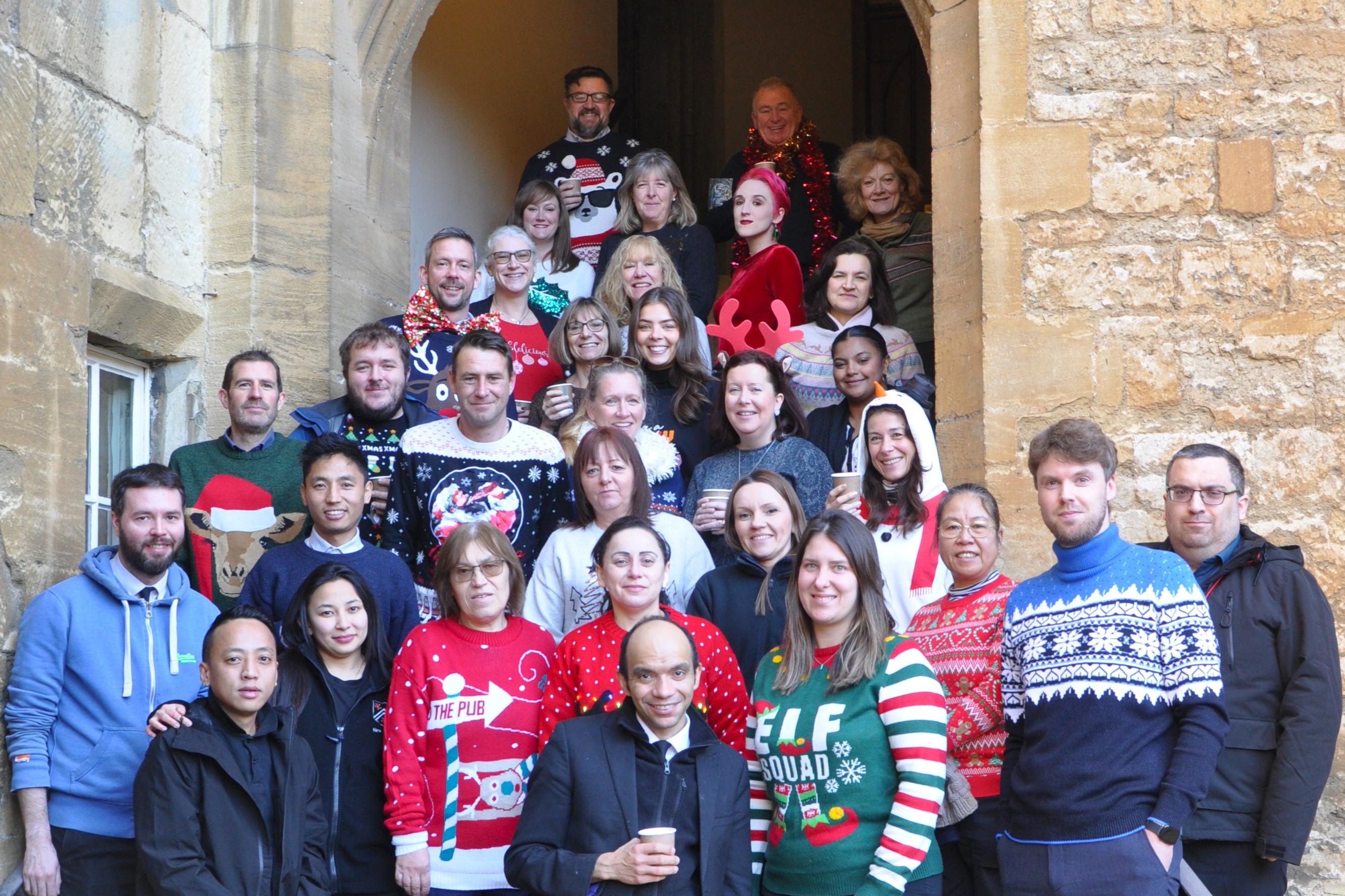 Staff in Christmas jumpers on the Hall stairs