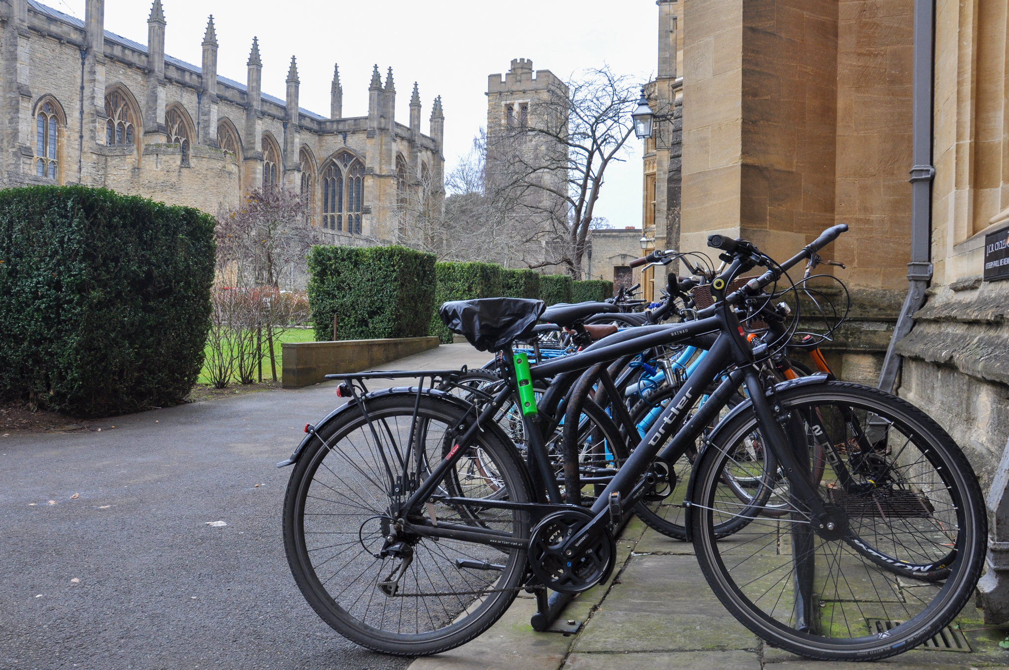 Bicycles parked at dedicated racks, with gothic chapel and bell tower in background