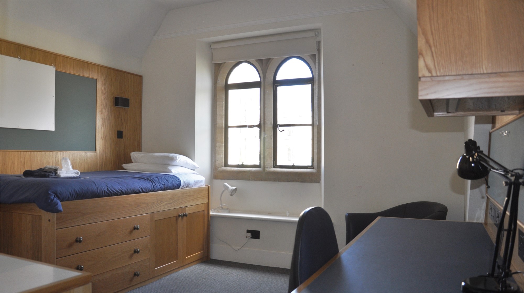 Student bedroom with bed, window, and desk