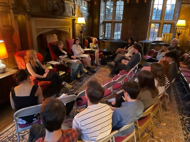 A group of people sitting in chairs in an old, wood-panelled room