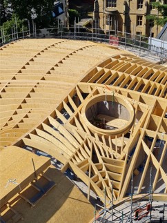 A curved timber roof structure, with a circle in the centre