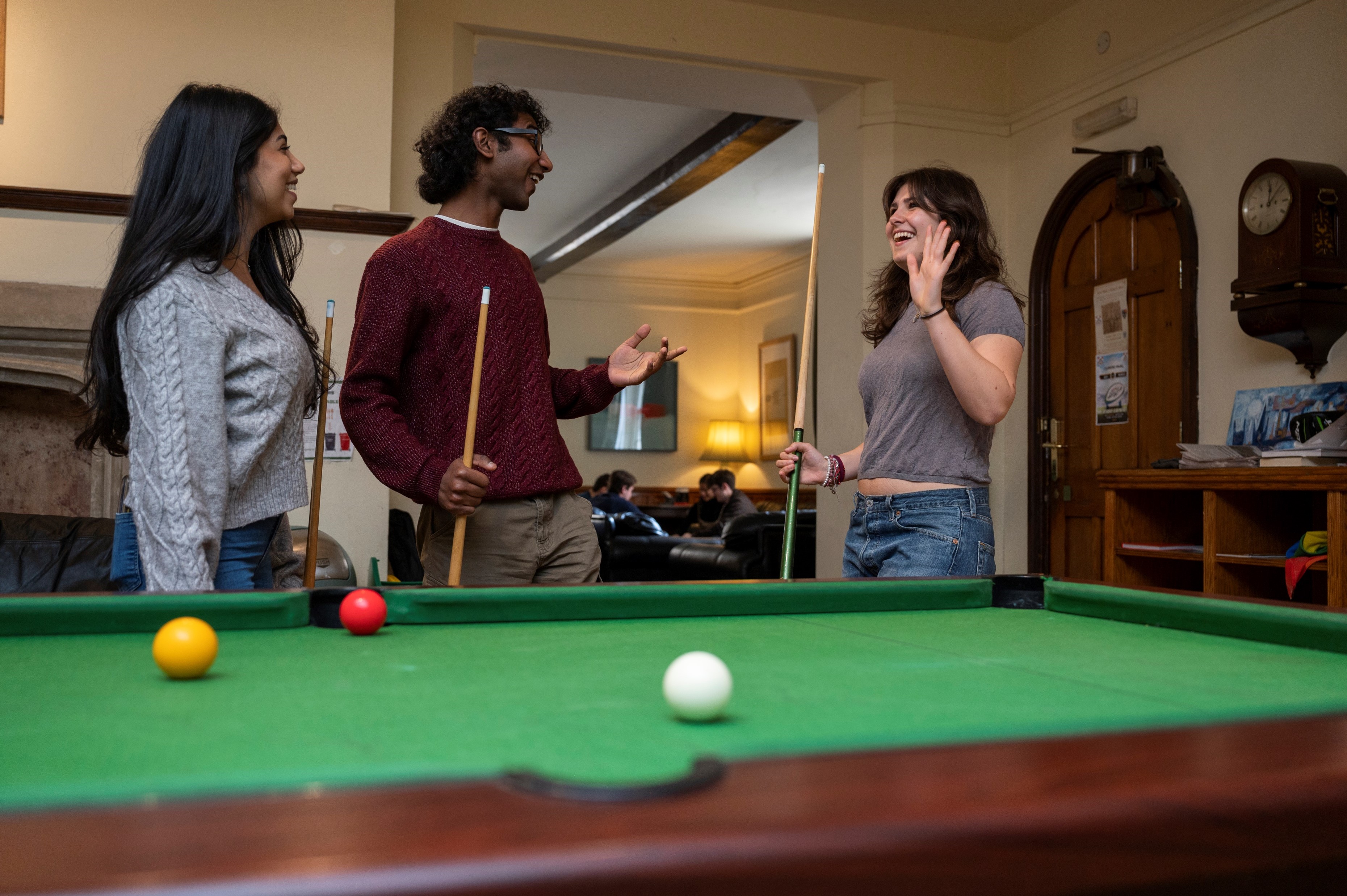 Three students play a game of pool in the JCR