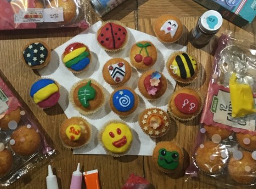 Cupcakes decorated with the rainbow flag, New College crest and other designs