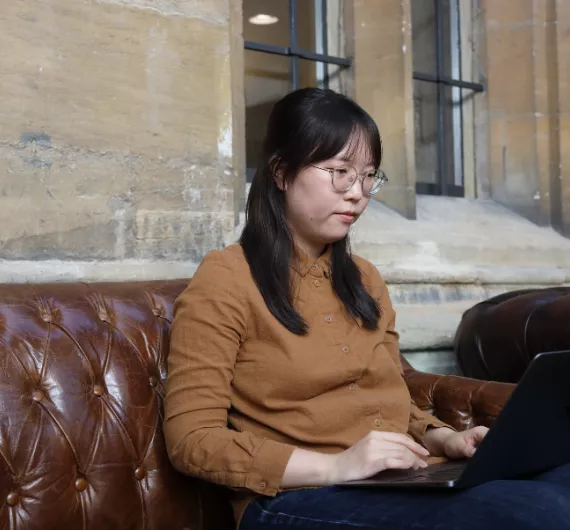 A postgraduate student sits on their laptop in the bar
