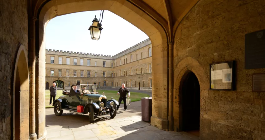 Old Morris car framed by arch in New College Front Quad
