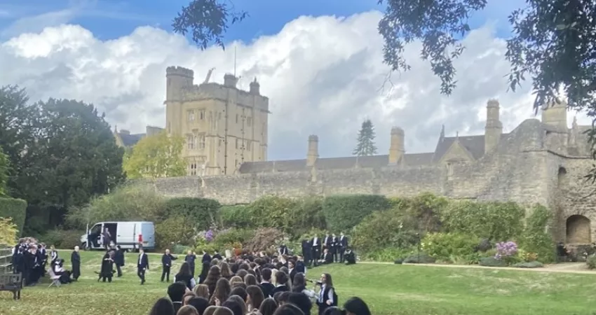 Students lining up for photographs in the Gardens, with the Robinson Tower and City Wall in the background