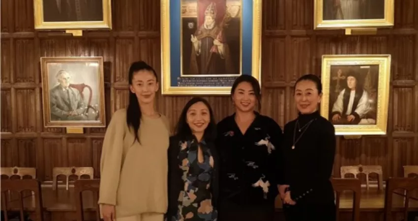 Four people smiling in front of old paintings