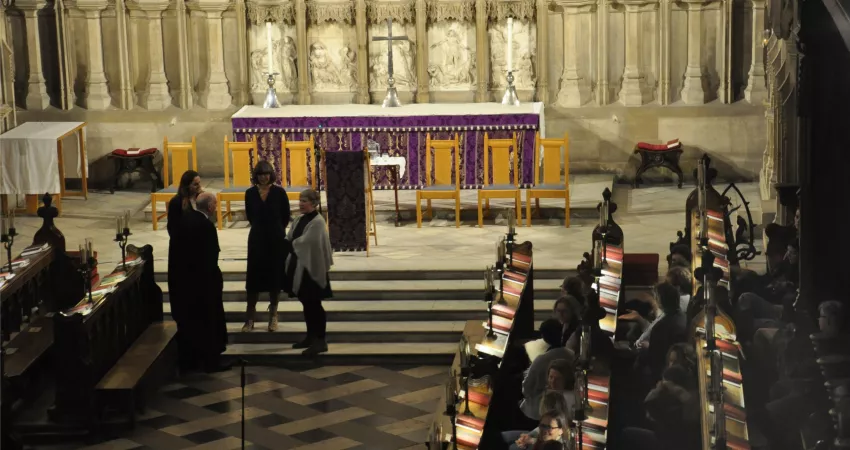 A group of people standing in front of an altar, with an audience waiting for them to speak