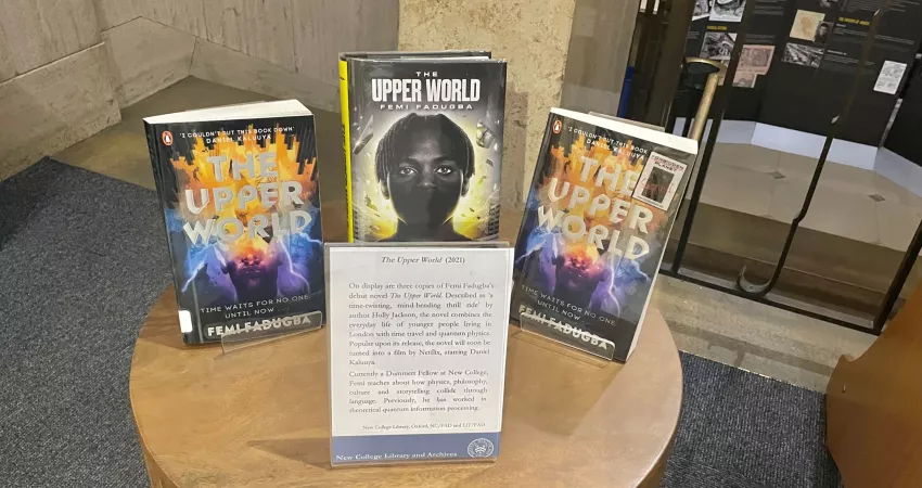 A table with three copies of 'The Upper World' (book) on