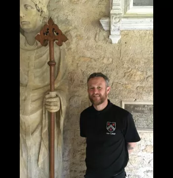 Brendan standing next to a statue with a wooden staff (that he created)