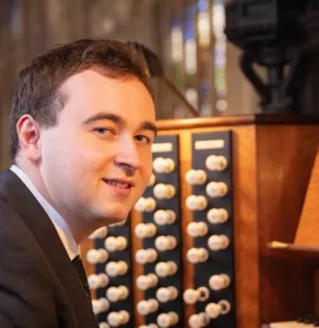 Donal McCann smiling in front of an organ