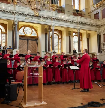 Choir singing with elaborate interior of a building in the background