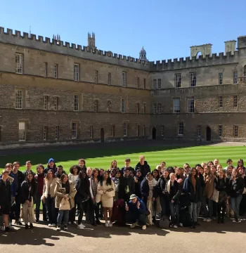A large group of students standing in a medieval quadrangle